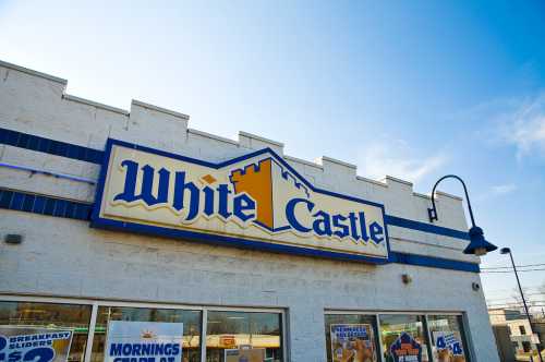 Signage of a White Castle restaurant against a clear blue sky.