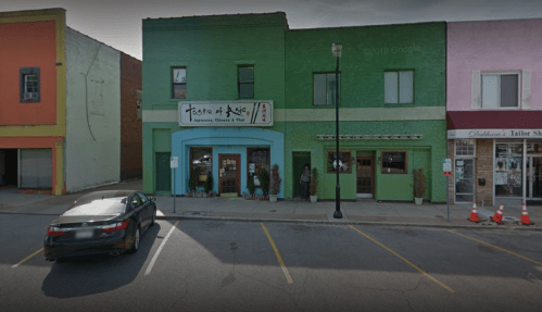 A colorful building with a sign for "Taste of Magic," featuring Japanese, Chinese, and Thai cuisine, in a small town.