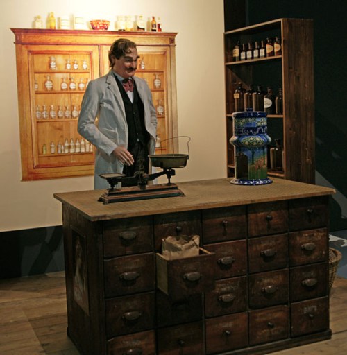 A vintage apothecary scene featuring a man in a lab coat, scales, and a wooden cabinet filled with jars.