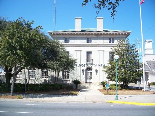 Valdosta City Hall, a historic building with a white facade, surrounded by trees and clear blue skies.