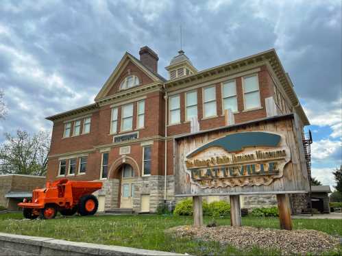 Historic brick building with a sign for the Mining & Rollo Jamison Museums in Platteville, featuring an orange tractor in front.