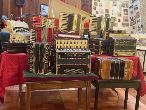 A collection of various accordions displayed on tables, featuring different colors and designs in a cozy setting.