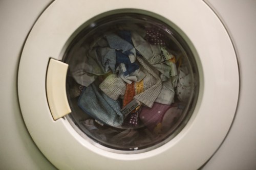 A close-up of a washing machine door showing a colorful load of laundry inside.