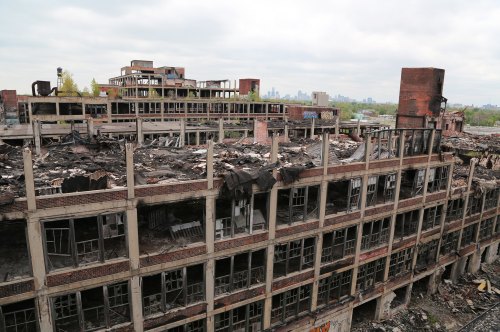 Aerial view of a dilapidated, burned-out industrial building with broken windows and crumbling structures.