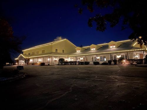 A yellow building illuminated with string lights at night, surrounded by trees and a dark sky.