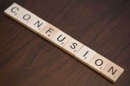 Scrabble tiles arranged to spell "CONFUSION" on a wooden surface.