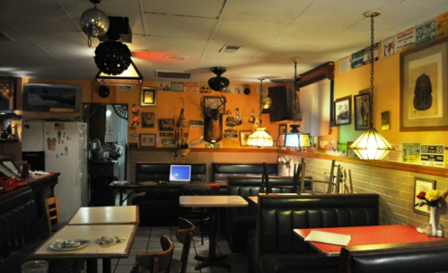 Cozy diner interior with booths, vintage decor, and warm lighting, featuring a disco ball and various wall art.