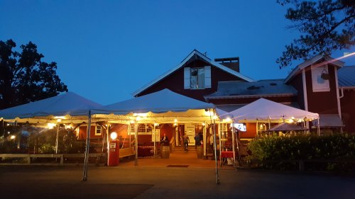 A red building with a tent lit up at night, people gathered outside, creating a warm and inviting atmosphere.