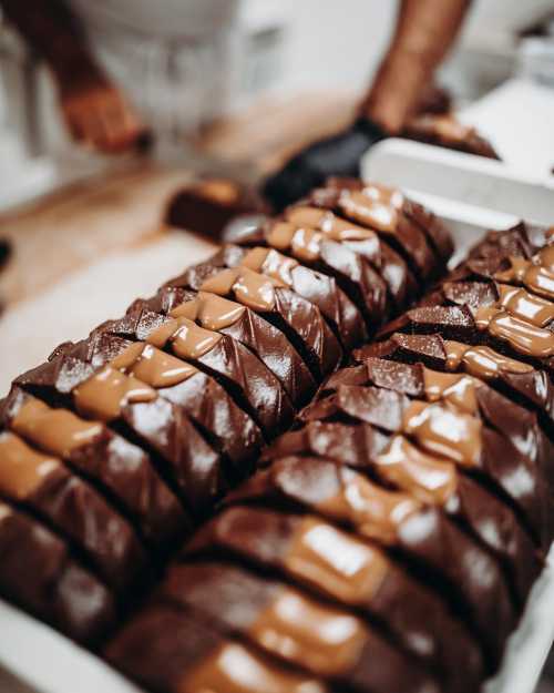 Close-up of neatly arranged chocolate bars topped with caramel, showcasing a rich, glossy texture.