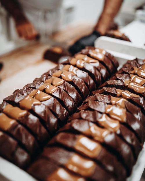Close-up of neatly arranged chocolate bars topped with caramel, showcasing a rich, glossy texture.