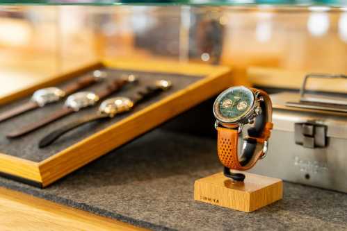 A stylish watch on a display stand, with a selection of leather watch straps in the background.