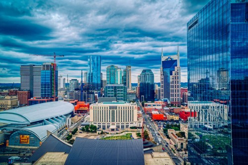 Aerial view of a vibrant city skyline with modern skyscrapers and a cloudy sky in Nashville, Tennessee.