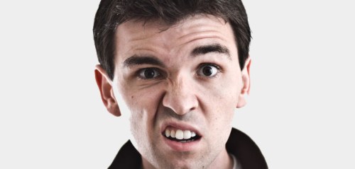A young man making a confused or displeased facial expression against a plain background.