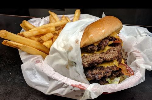 A large cheeseburger with multiple patties and melted cheese, served with a side of golden French fries.