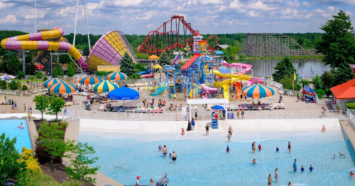 A vibrant water park with slides, pools, and roller coasters, filled with people enjoying a sunny day.