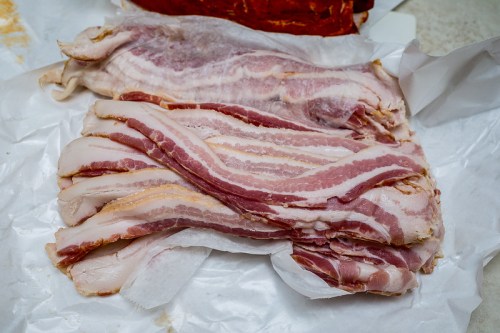 Raw bacon strips laid out on white parchment paper.