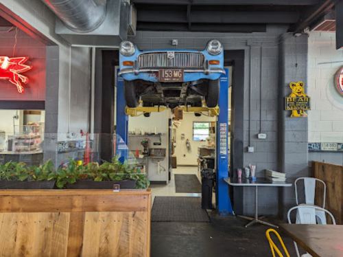 A vintage car is suspended above an entrance in a restaurant, with a kitchen visible in the background.