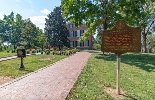 Historic site of Federal Hill, a brick house with a marker, surrounded by greenery and a paved pathway.