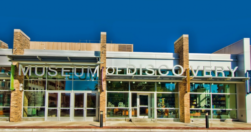 Exterior view of the Museum of Discovery, featuring large glass doors and a modern brick facade.