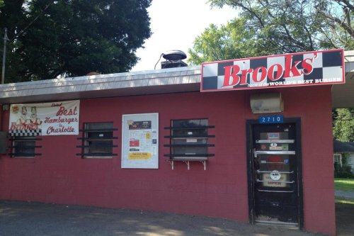 Exterior of Brooks' restaurant, featuring a red facade, signage for "Best Hamburger" and a takeout window.