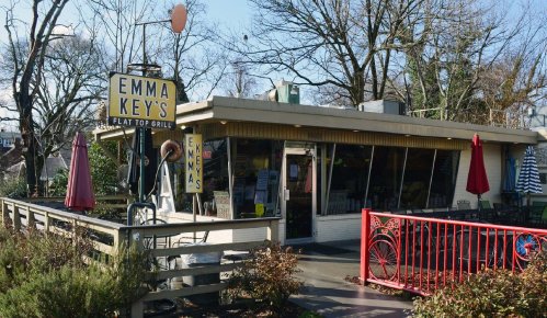 Exterior of Emma Key's Flat Top Grill, featuring a sign, outdoor seating, and trees in the background.