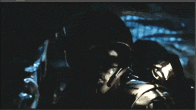 A close-up of a soldier in dark, tactical gear, illuminated by dim light, suggesting a tense or dramatic atmosphere.