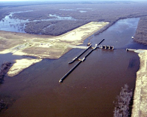 Aerial view of a river lock system with surrounding land and trees, showcasing water management infrastructure.