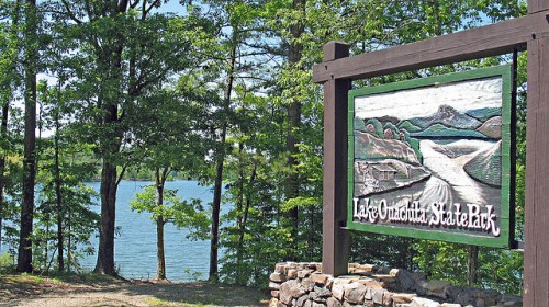 Sign for Lake Catawba State Park with a scenic view of the lake and trees in the background.