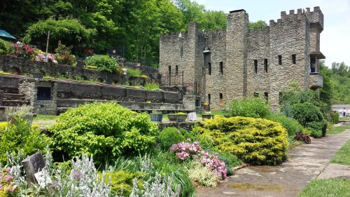 A stone castle surrounded by lush greenery and colorful flowers in a serene garden setting.