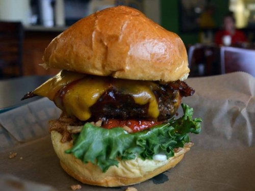A juicy burger with melted cheese, bacon, lettuce, tomato, and sauce, served on a toasted bun.