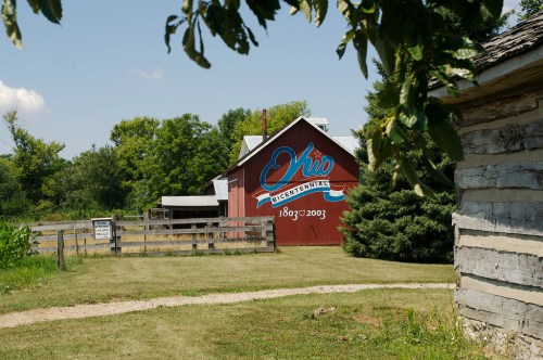A red barn with a mural reading "Ohio 1803-2003" surrounded by green fields and trees on a sunny day.