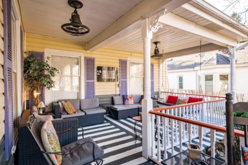 A cozy porch with striped flooring, comfortable seating, and decorative plants, featuring a TV on the wall.