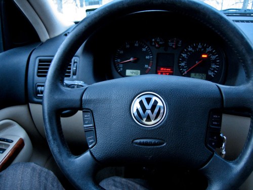 Close-up of a Volkswagen steering wheel and dashboard, showing speedometer and controls.