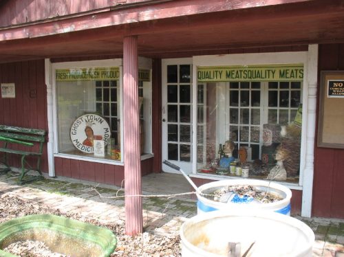 A rustic storefront with large windows displaying various products and a sign for quality meats.