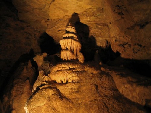Stalactites and stalagmites in a dimly lit cave, showcasing unique rock formations.
