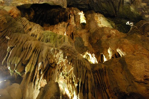 Stalactites and rock formations illuminated in a cave, showcasing intricate textures and natural beauty.