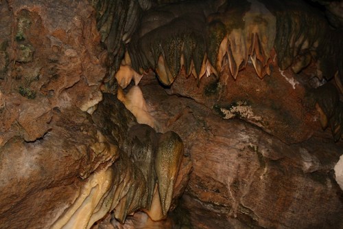 Close-up of textured cave walls with sharp, stalactite-like formations and earthy tones.