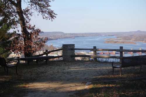 Scenic view from a lookout point overlooking a river, with benches and trees in the foreground.