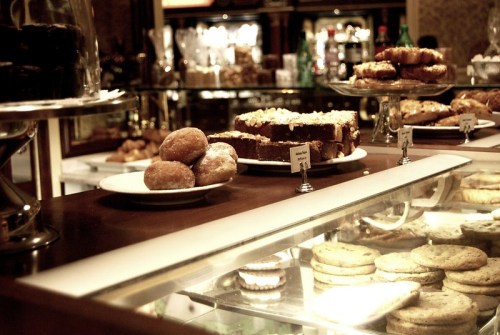 A display of assorted baked goods, including brownies, donuts, and cookies, in a cozy bakery setting.