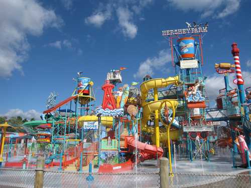 Colorful water park with slides and attractions under a blue sky, featuring various water play areas and structures.