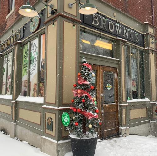 A festive storefront with a decorated Christmas tree in the snow, featuring the name "Browne's" on the building.