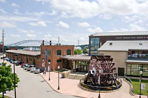 A view of the National Mississippi River Museum with a large waterwheel in the foreground and a bridge in the background.