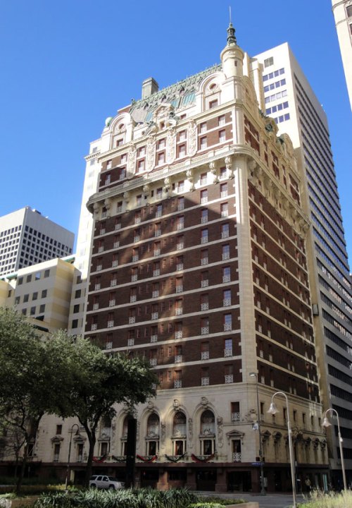 Historic building with ornate architecture, featuring a mix of brick and stone, surrounded by modern skyscrapers.
