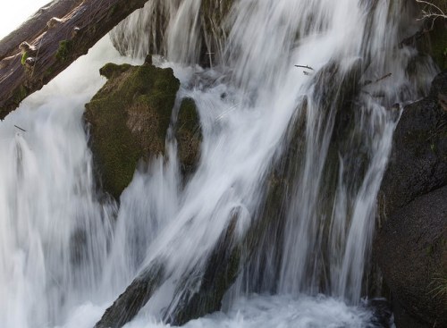 A close-up of a waterfall cascading over moss-covered rocks, creating a misty, serene atmosphere.