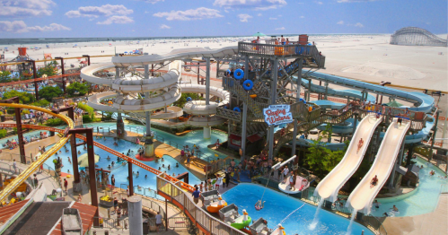 A vibrant water park with slides, pools, and visitors enjoying a sunny beach day.