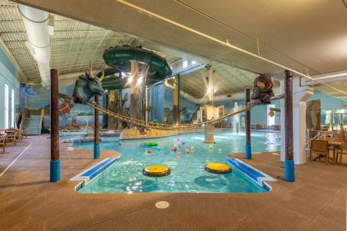 Indoor water park featuring a pool with slides, playful decorations, and floating toys.