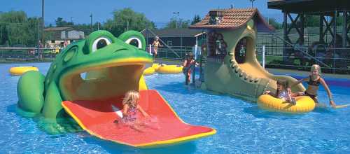 A colorful water park scene with a frog slide, children playing in the pool, and a whimsical play structure.