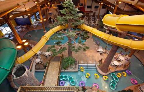 Aerial view of an indoor water park featuring slides, a pool, and seating areas surrounded by tropical decor.