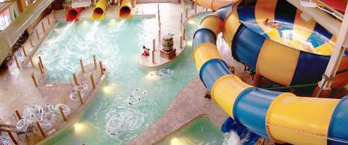 Indoor water park featuring colorful slides, a lazy river, and a pool area with guests enjoying the water.