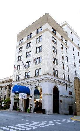 Historic six-story building with a blue awning, featuring flags and a welcoming entrance on a city street.